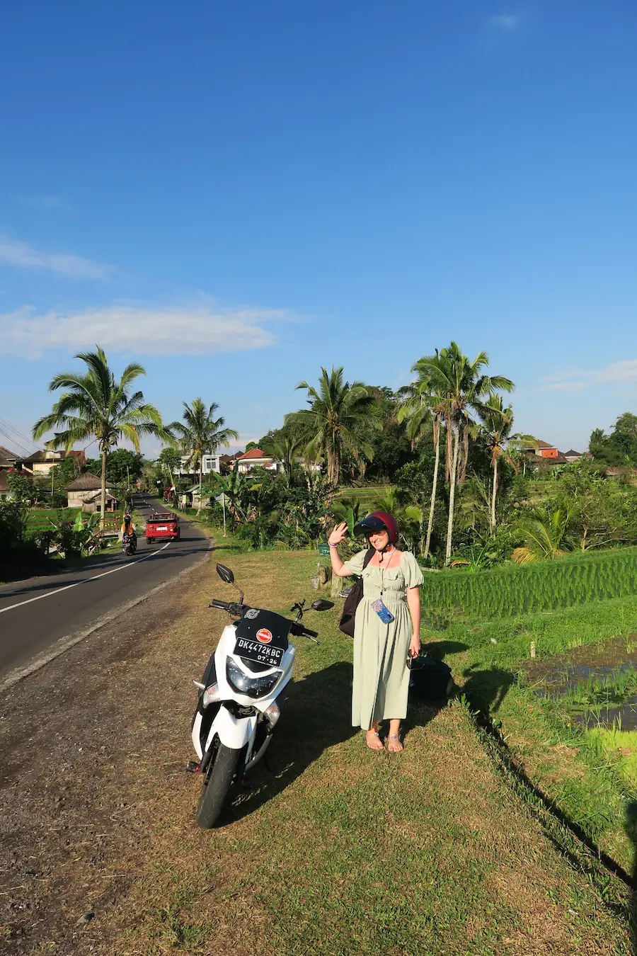 Saludando a cámara al llegar en moto a las terrazas de arroz de Jatiluwih, Bali. Waving at the camera upon arriving by motorbike at Jatiluwih Rice Terraces, Bali.